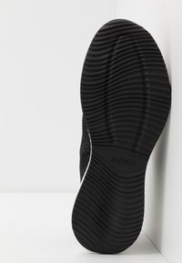 Semelle de chaussure en caoutchouc noir avec des rainures texturées et ondulées et le nom de la marque "BOBS" embossé au centre.