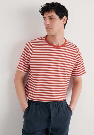 Rød og hvid stribet kortærmet t-shirt med rund hals, parret med mørkeblå sweatpants med snoretræk. Glat stofstruktur.