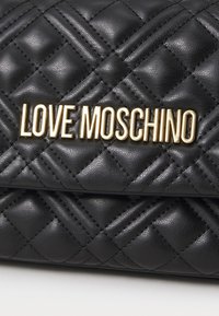 Borsa a tracolla nera in pelle sintetica trapuntata con logo dorato "LOVE MOSCHINO". La superficie presenta un caratteristico motivo a diamante.