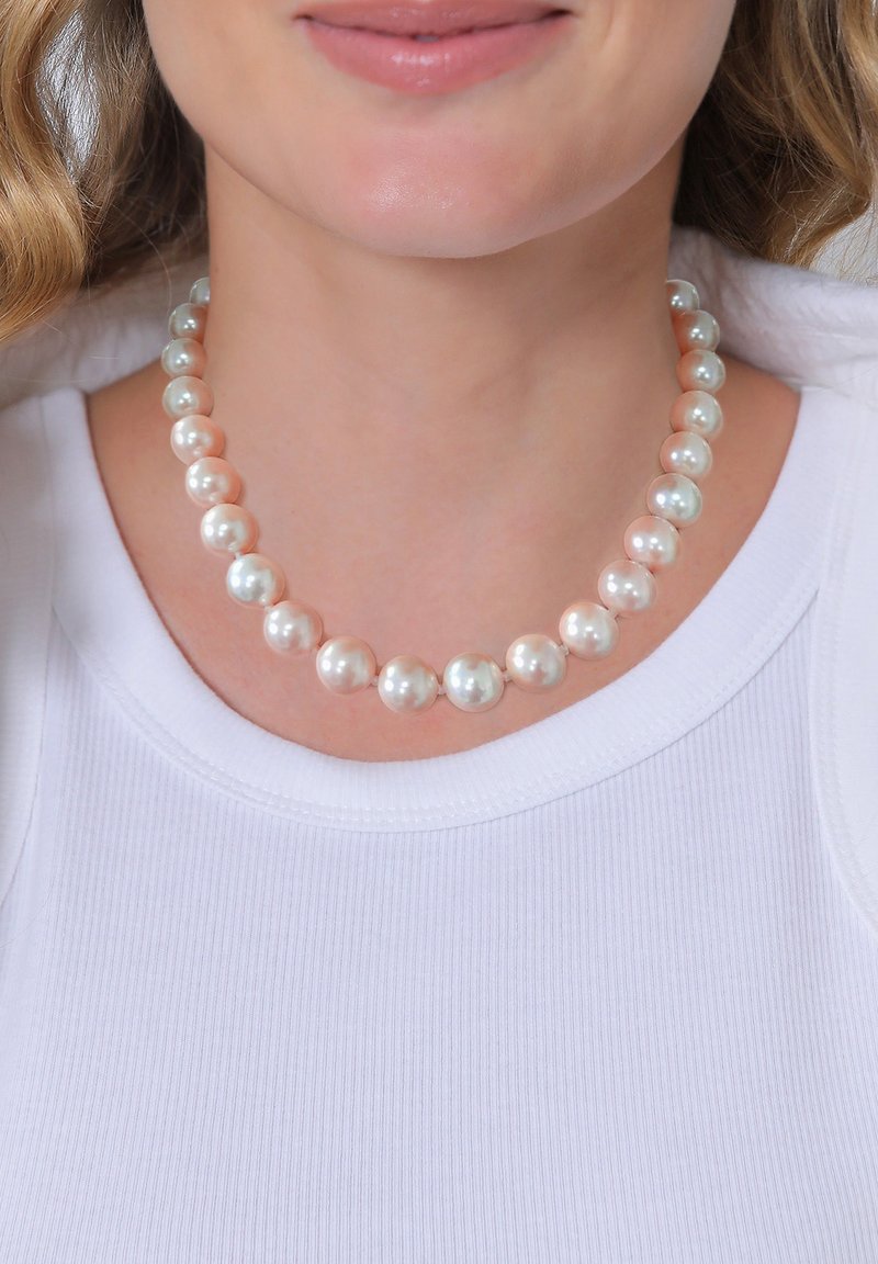 Perlenkette mit abwechselnd kreidig-weißen und hellrosa runden Perlen auf einem schlichten Strang, getragen über einem weißen gerippten Oberteil.