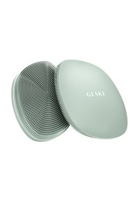Brosse à cheveux fine et ovale de couleur vert doux. Le dessus présente une finition lisse avec un logo, tandis que le dessous est doté de poils ronds, denses.