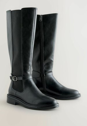 Schwarze kniehohe Stiefel aus Leder mit glatter Oberfläche, seitlichem Reißverschluss und einem dekorativen Riemen mit einer silbernen Schnalle. Niedriger Blockabsatz.