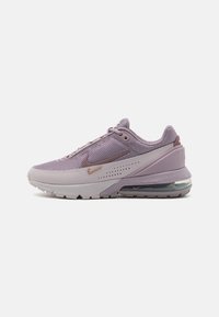 Violetti Nike Air Max -kengät, joissa on verkkomateriaali yläosassa, pehmeä välipohja ja kumipohja. Kengissä on erottuva ilmapatja kantapäässä ja metalliset yksityiskohdat.