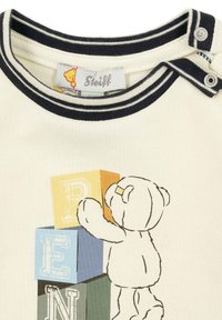Baumwoll-T-Shirt mit navyblauem gestreiften Ausschnitt. Zeigt eine Bärenillustration, die farbige Blöcke (gelb, blau, grün, orange) mit Buchstaben stapelt.