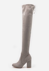 Botas de ante gris hasta la rodilla con un tacón grueso en bloque. Presentan una textura suave y un diseño de tipo pull-on con puntera redondeada.