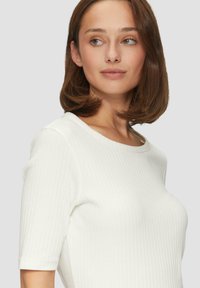 Weißes, geripptes Kurzarmoberteil mit Rundhalsausschnitt, das eine glatte Textur und eine taillierte Silhouette aufweist.