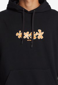Sudadera negra de algodón, con un diseño gráfico floral en naranja en el pecho. Cuenta con un bolsillo frontal y capucha con cordón.