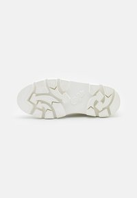 Biała podeszwa sneakerów z teksturowanym wzorem bieżnika. Zawiera solidny materiał gumowy, grubą profil oraz wytłoczone logo z boku.