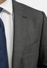 Grå ullkostym med en texturerad yta, med ett enkelt ficka på jackan och en skarp vit skjorta under ett marinblått slips.