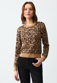 Sweter w panterkę w odcieniu brązowym z czarnymi plamami, z prążkowanymi mankietami i dołem. Materiał sprawia wrażenie dzianiny, dopasowany fason z okrągłym dekoltem.