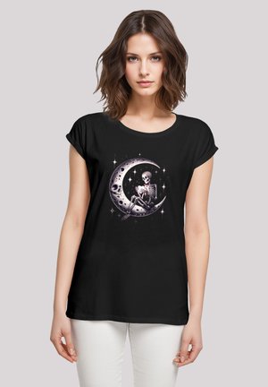 Schwarzes Baumwoll-T-Shirt mit einem Design, das ein Skelett zeigt, das auf einem Mond in Halbmondform sitzt. Der Druck enthält Sternakzente und Details in Weiß- und Grautönen.