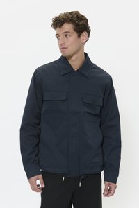 Chaqueta ligera azul marino con un diseño de corte recto, cierre de botones, dos bolsillos en el pecho y cordón ajustable en el dobladillo.