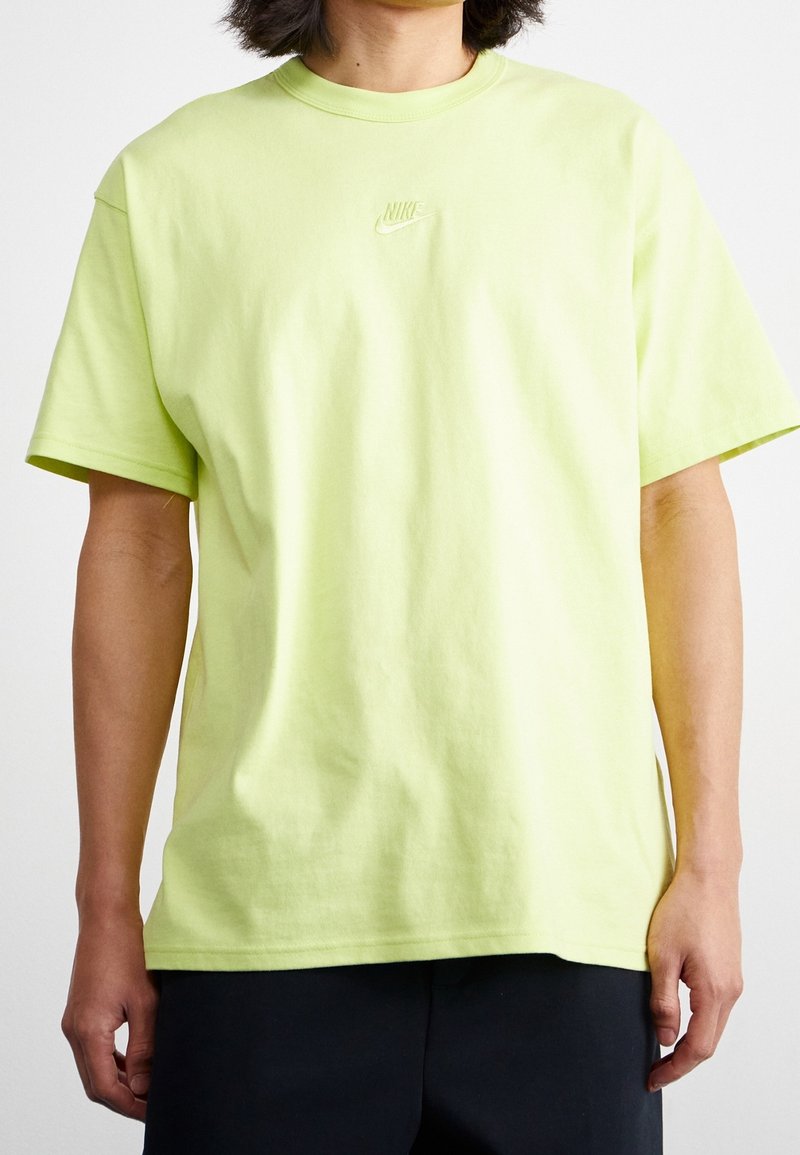 Ljusgrön bomullströja med rundad halsringning, korta ärmar och en subtil Nike-logga broderad i mitten. Slät textur.