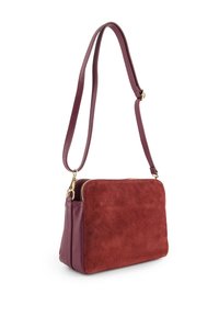 Burgundy crossbody bag featuring smooth leather and soft suede textures, a zipper closure, and an adjustable strap.