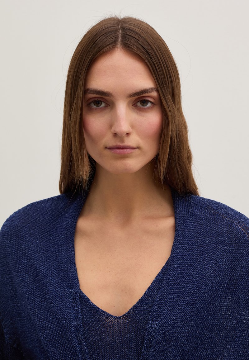 Marineblauer Strickpullover mit tiefem V-Ausschnitt und offenem Frontbereich, featuring eine strukturierte Optik und eine relaxed Passform.