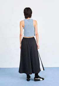 Blå ribbestrikket crop topp kombinert med et svart, strømlinjeformet skjørt med en hvit sidelinje, fullført med svarte sneakers.