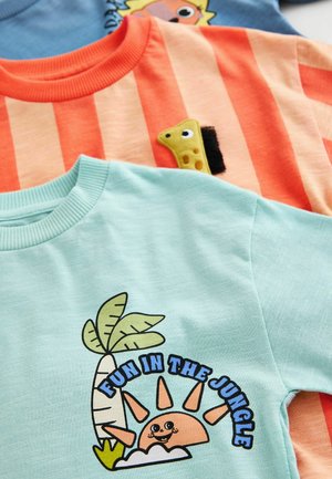 Three short-sleeve t-shirts: one mint green with a graphic print, one orange with stripes, and one light blue with a cartoon design.