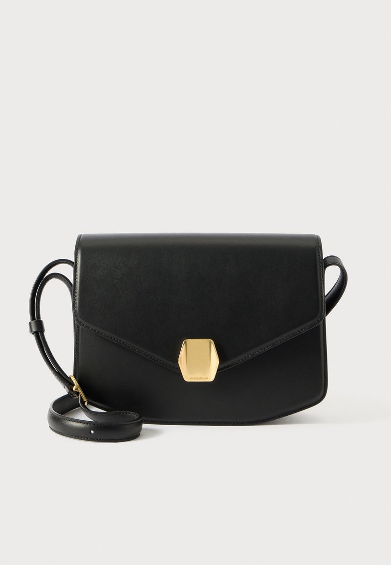 Bolso de mano de cuero negro con forma rectangular, cierre magnético y acentos en tono dorado. Cuenta con una correa desmontable para mayor versatilidad.