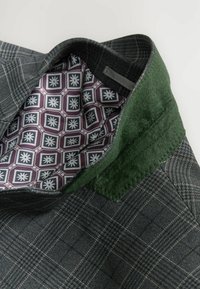 Gray plaid jacket with a green felt collar and a patterned purple lining featuring hexagonal shapes and floral designs.