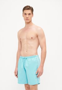 Akvablå badshorts med elastisk midje og snøring. Har tre hvite striper langs sidene og logo på venstre ben.
