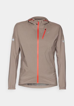 Leichte, beige Jacke mit einer taillierten Kapuze; mit leuchtend orangefarbenen Reißverschlüssen und Akzenten, elastischen Bündchen und einem schlanken Design.