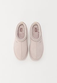 Roze suède slipper met een zachte bontvoering, gevlochten rand en een reliëflogo aan de zijkant. Rond neu, en een flexibele zool.