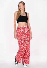 Rode en witte geblokte wijde broek met een elastische tailleband, gecombineerd met een zwarte cropped tanktop en zwarte lage sneakers.