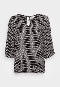 Blouse noire et blanche en tissu léger avec un motif géométrique, dotée d'une encolure découpée en forme de goutte et de manches trois-quarts.