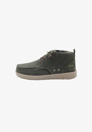 Chaussures en cuir vert foncé pour homme avec un dessus lisse, des lacets marron, une semelle en caoutchouc et une doublure intérieure à motif. Logo Jeep sur le côté.