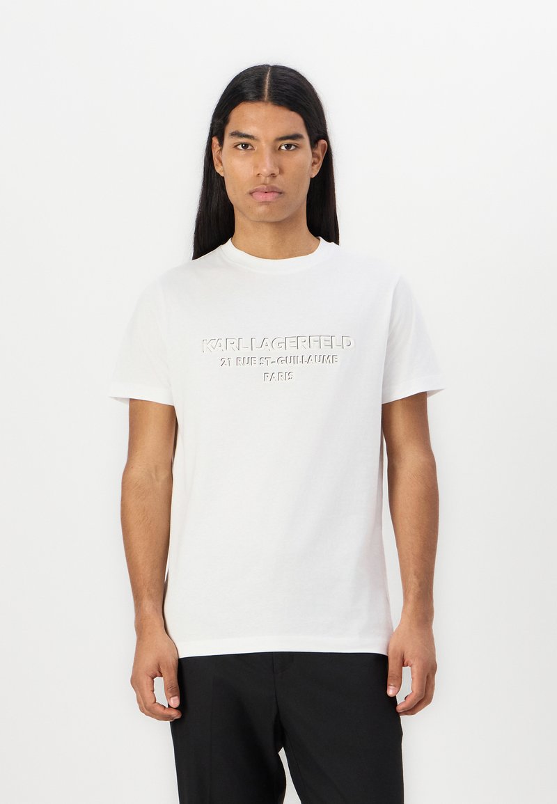 Balta medvilnė t-marškiniai su iškilia "KARL LAGERFELD" logotipu. Trumpomis rankovėmis, apvaliu iškirpimu, įprasto kirpimo. Glotni tekstūra, minimalistinis dizainas.