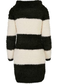 Luddigt stickad tröja i svart och gräddfärgade ränder, med en båtkrage och långa ärmar, samt en texturerad yta.