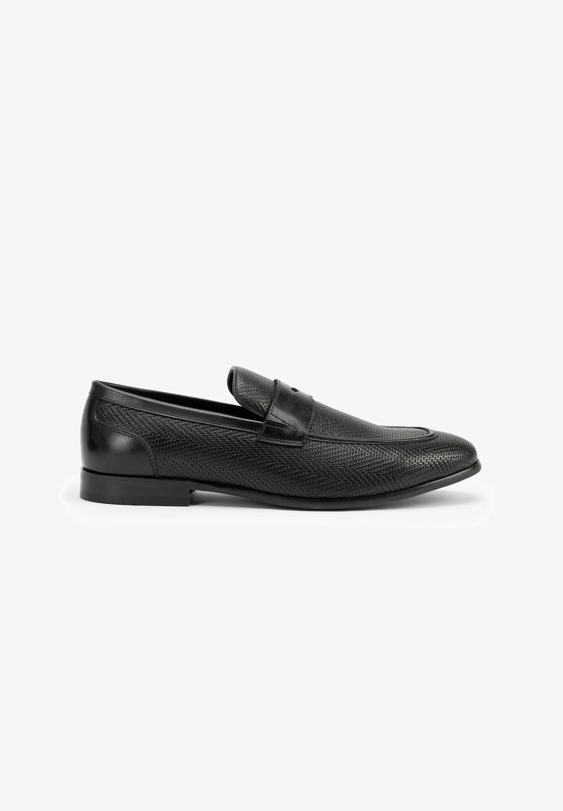 Mocasines de cuero negro con un upper texturizado, puntera redondeada y una correa única en el empeine. Diseño sin cordones con un tacón bajo.