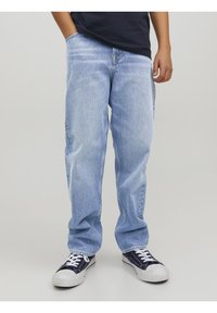 Jeans de mezclilla azul claro con un corte relajado, que cuentan con cinco bolsillos y costuras visibles. Llevados con zapatillas de deporte azul marino.