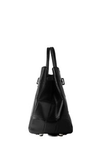 Sac à main en cuir noir avec doubles poignées supérieures, forme trapézoïdale structurée et pieds métalliques argentés sur fond blanc.