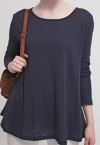 Granatowa, długorękawowa koszula z lekkiego materiału, z okrągłym dekoltem i luźnym krojem, o subtelnej teksturze.