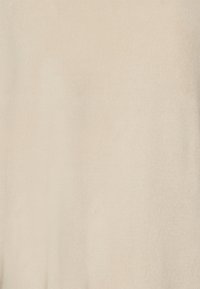 Tessuto di maglia beige con una superficie liscia e cuciture fini, che mostra sottili variazioni di tonalità.