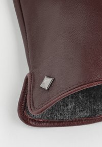 Guanto in pelle marrone con bordo in lana nera e piccolo ornamento metallico quadrato in cima.