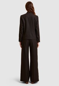 Donkerbruine gestreepte pakken set met een op maat gemaakt jasje en wijde broek. Textuurstof met een gladde afwerking en minimale details.