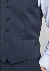 Gilet bleu marine avec une coupe ajustée, doté de cinq boutons marron, d'une poche poitrine unique et d'une finition lisse au toucher.