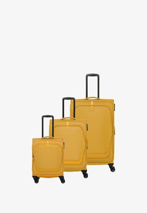 Trois valises rigides jaunes de tailles variées présentent des surfaces texturées, des poignées rétractables noires et des roues lisses pour la mobilité.