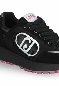 Sneaker nera con finiture in suede e lucido. Presenta un logo bianco, lacci neri e una suola in gomma rosa con grip testurizzato.