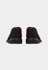 Ζευγάρι σκούρα καφέ δερμάτινα παπούτσια για επίσημες περιστάσεις, σε θέα από πίσω, με μαύρες σόλες και μπεζ ραφές κατά μήκος των άκρων.