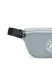 Borsa in nylon azzurro chiaro con zip frontale, fibbia nera e logo circolare. Texture morbida, design compatto e materiale resistente.