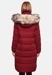 Red puffer coat with a hood, featuring a faux fur collar. The design includes vertical quilted sections and a long silhouette.