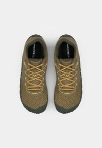 Zapatillas deportivas marrones con parte superior de malla texturizada, cordones amarillos en contraste y suela de goma oscura; cuentan con agujeros de ventilación y plantilla acolchada.
