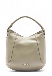Bolso estilo hobo en cuero beige suave con una parte superior amplia y curva, asa con tachuelas y logo de la marca en dorado en la base. Textura lisa en general.