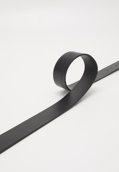 Cinturón de cuero negro con una textura suave, con un extremo redondeado y múltiples agujeros para ajuste, colocado en una posición enrollada.