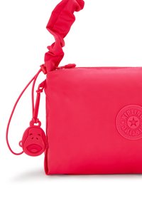 Kipling crossbody bag in bright pink, made of smooth nylon. Features a scrunched strap and monkey-shaped zipper pull. Embossed logo on the front.