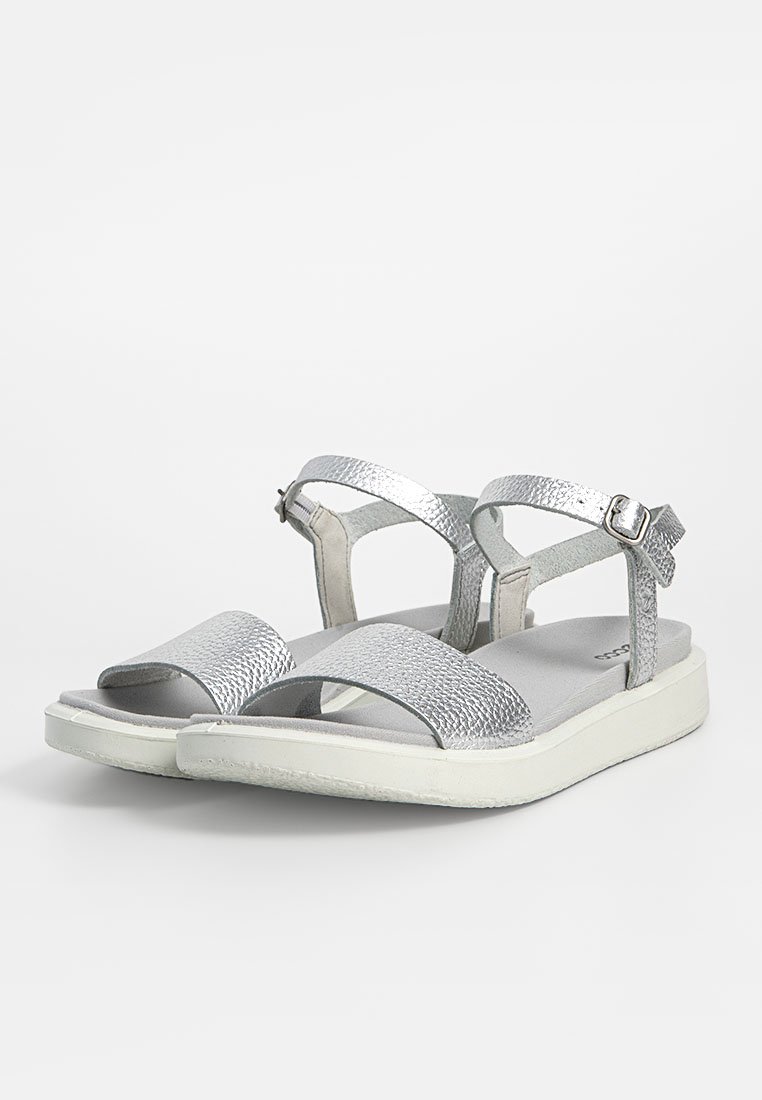 Silberne Sandalen mit strukturierten Riemen, flacher Sohle und verstellbaren Knöchelriemen. Sie verfügen über ein offenes Zehen-Design und eine leichte Polsterung.