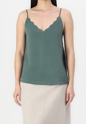 Haut sans manches vert foncé avec un décolleté festonné, en tissu lisse. Il a des bretelles réglables et une coupe décontractée, associé à une jupe plissée.
